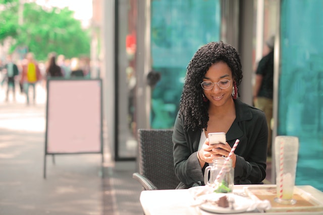 Mulher usando smartphone no restaurante como fazer marketing digital