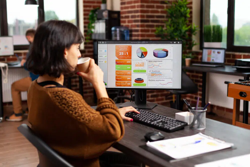 mulher trabalhando em uma agência de seo com a tela do computador mostrando os resultados do tráfego orgânico