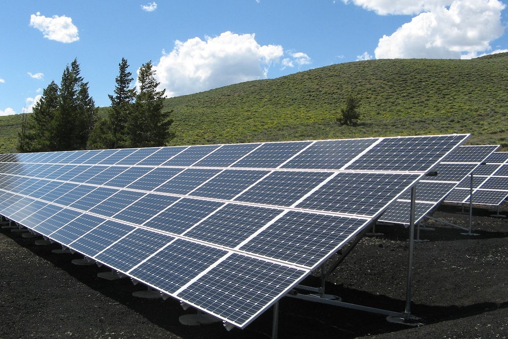 painéis de energia solar em uma área verde com gramado e céu azul
