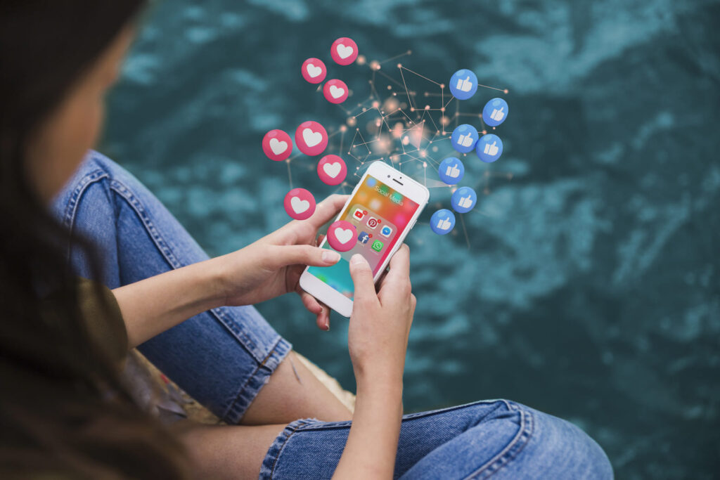 mulher segurando um celular com ícones das redes sociais Instagram TikTok e Facebook