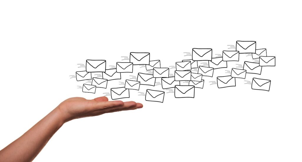 Montagem de foto e ilustração que mostra uma mão segurando ícones de e-mail marketing.